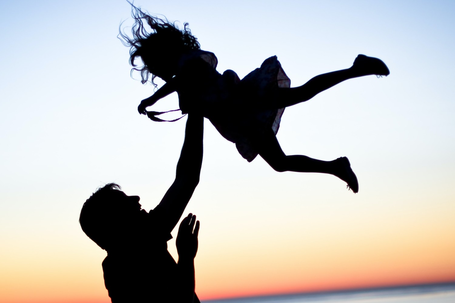 Man throwing girl in air