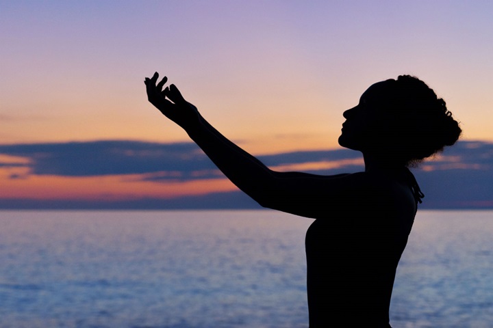 Silhouette of woman practicing Tai Chi on beach