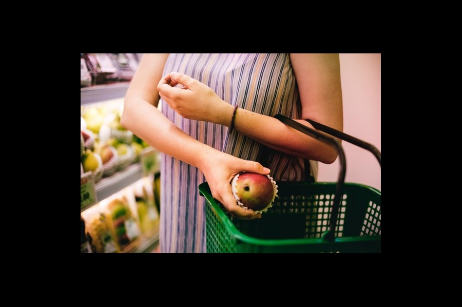 Shopper putting an apple into a shopping basket