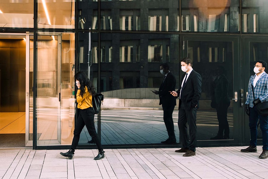 people with masks queueing in front of a building