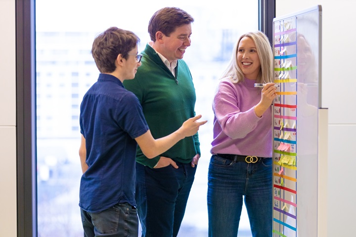 Three people working at a board