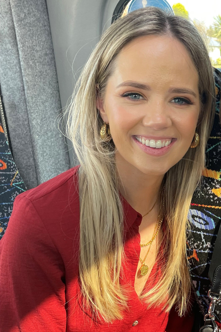 A woman in a red top and long blonde hair, smiling at the camera.