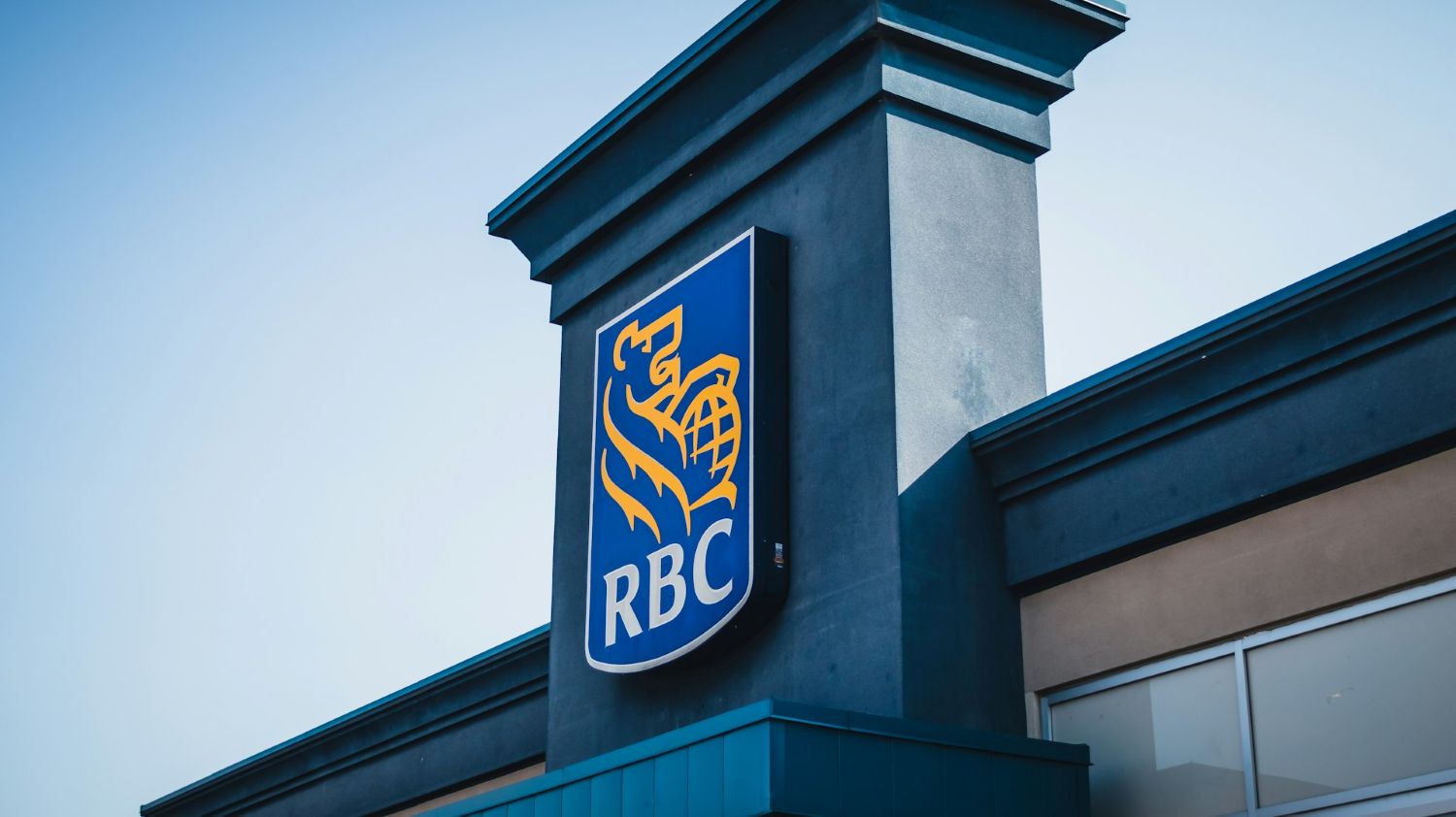 RBC logo displayed on the exterior of a modern building against a clear blue sky