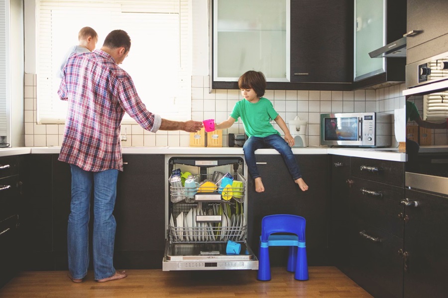 Man cleaning kitchen with small children