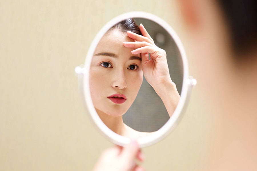 Chinese woman looking into mirror full