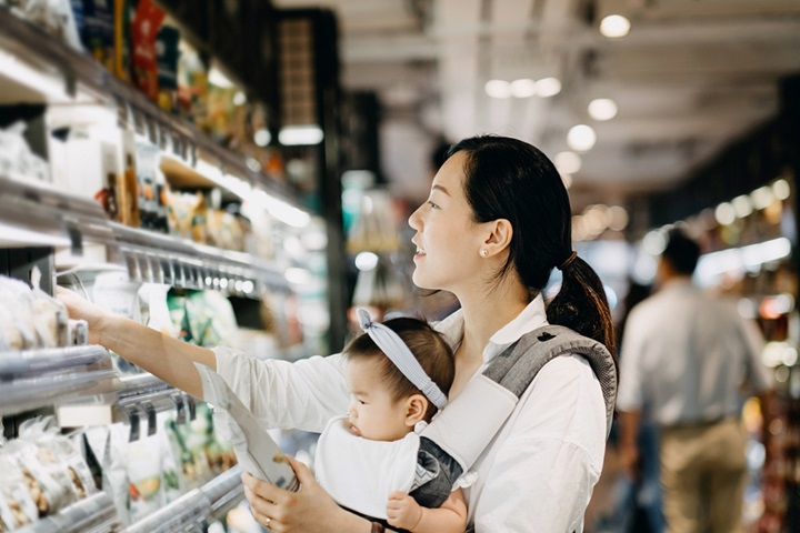 Young mother shopping in a supermarket with a baby.