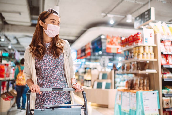 Pretty young woman with medical face mask shopping for daily necessities and groceries in supermarket