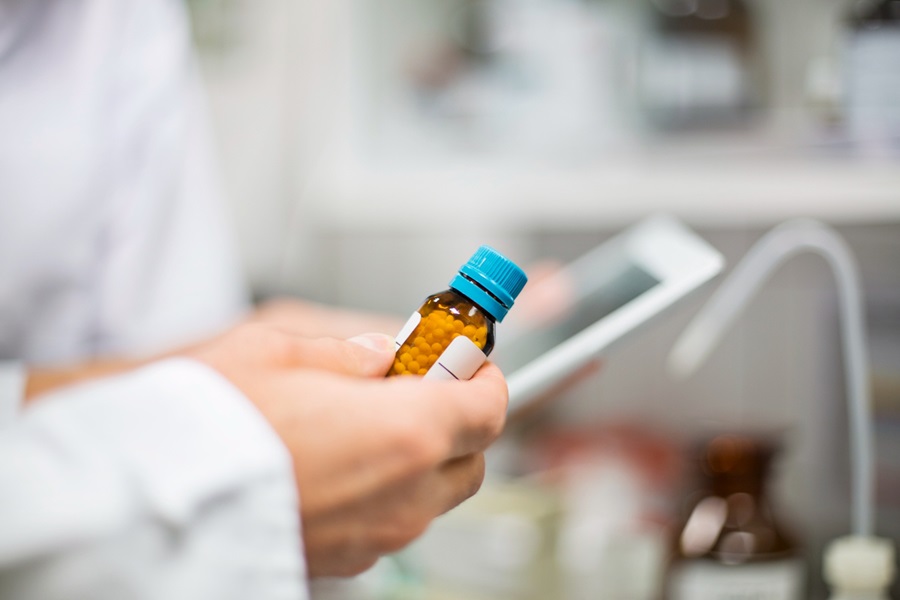 Scientist holding pill bottle and digital tablet