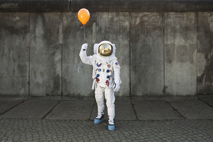 Space man holding a balloon in the street
