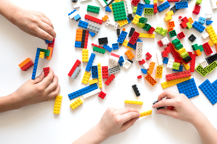 Hands playing with colorful LEGO blocks on a white background