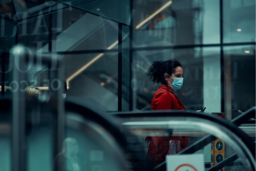 Woman wearing face mask going down an escalator on the tube