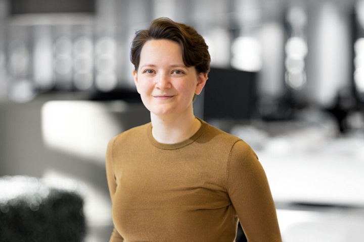 An image of Megan Cross, Head of Inclusion & Diversity. The background is black and white but Megan is in colour. She has short brown hair and also has a light brown jumper. 