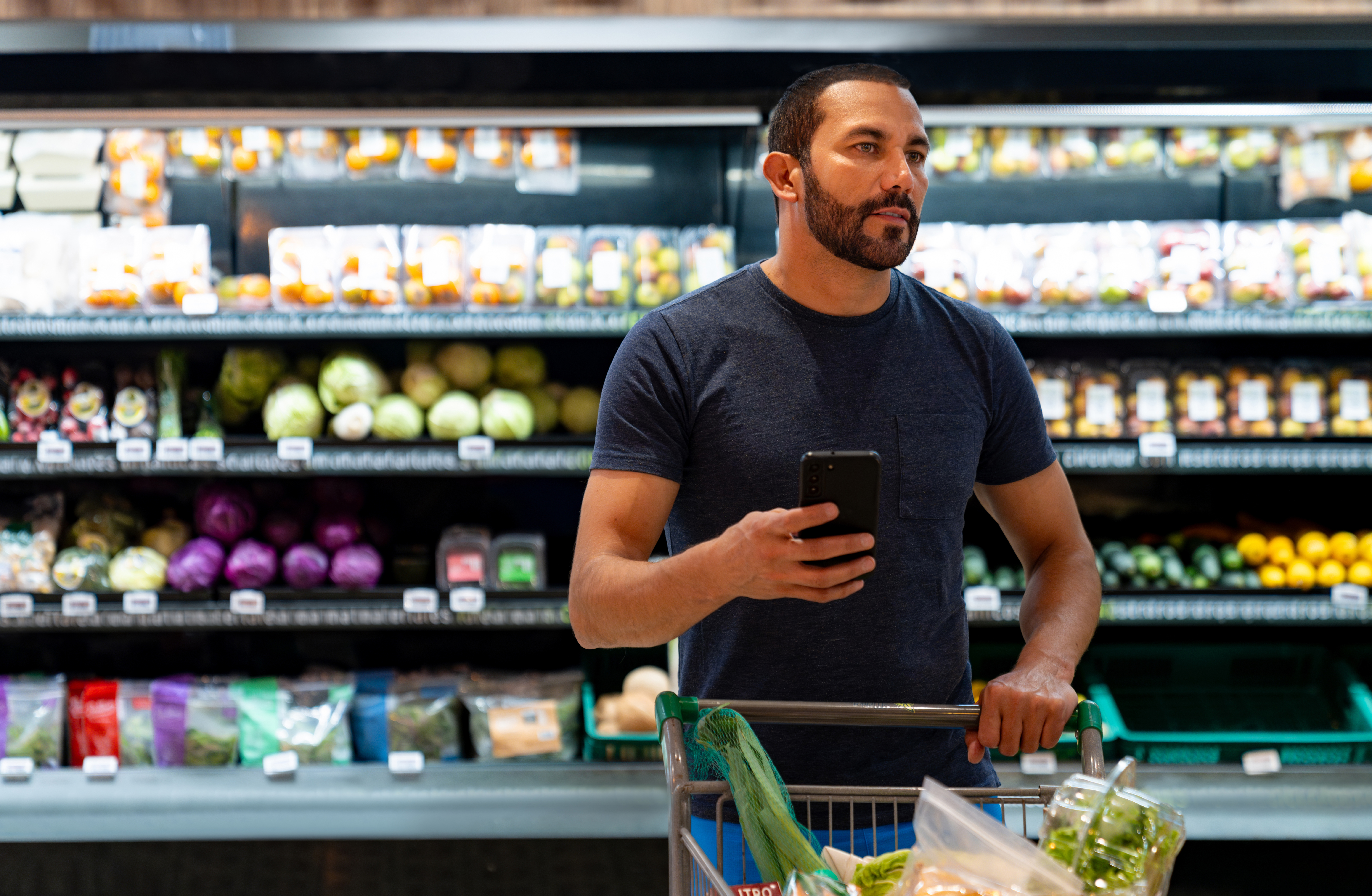 Man shopping in supermarket with list on his phone 