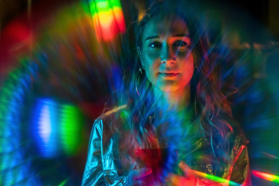 Young woman surrounded by rainbow coloured lights
