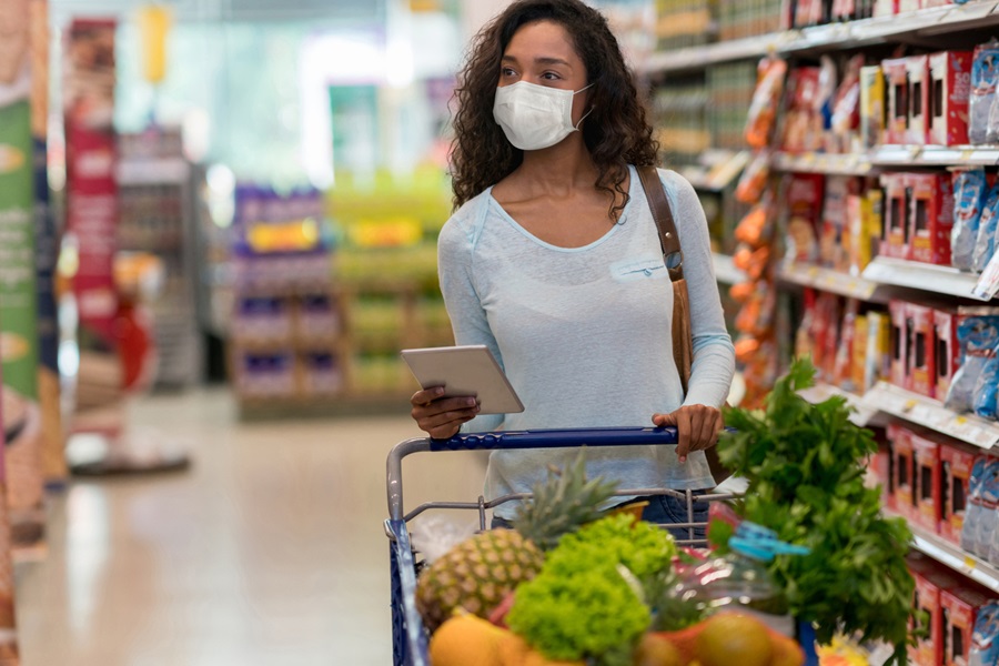 Young masked woman shops in supermarket