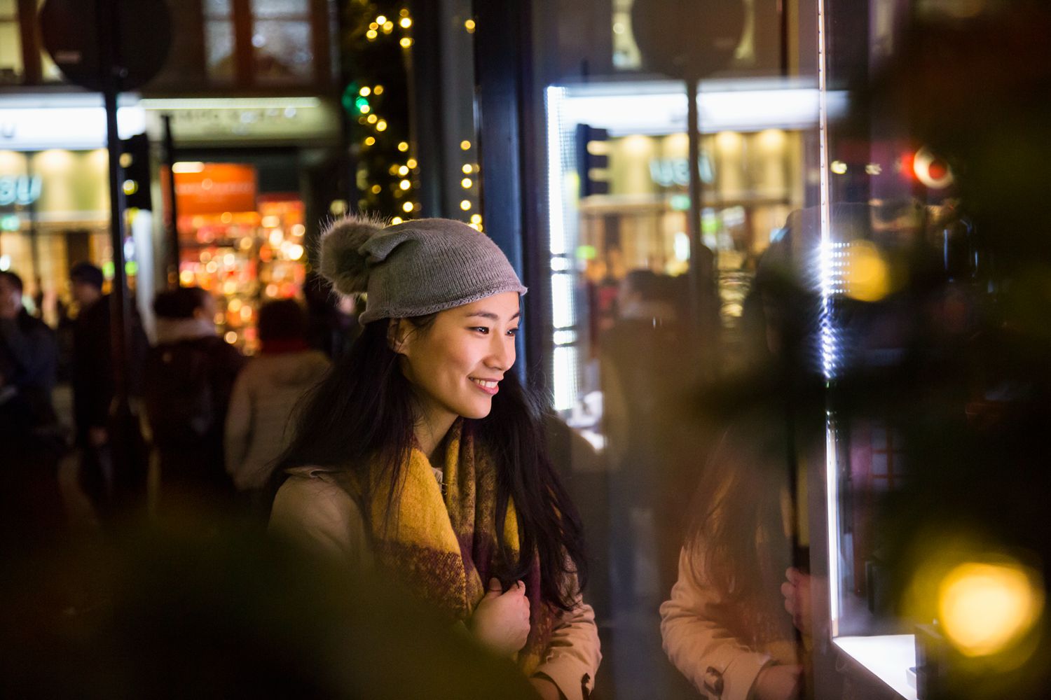 East Asian woman looking into shop window at evening.